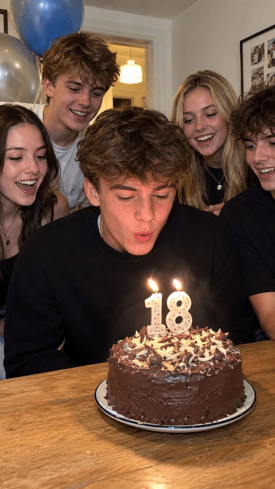 A young man blowing out the candles on his 18th birthday cake