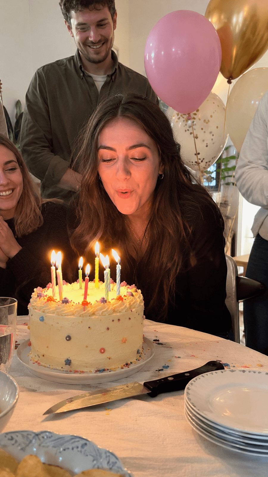 A woman blowing out the candles on her birthday cake as friends look on